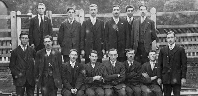 A group of men standing on a railway platform.