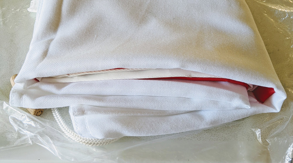 A folded flag, mainly white with some hints of red from the inner folds.