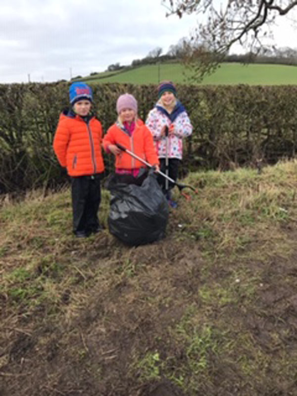 Three brightly dressed children litter picking